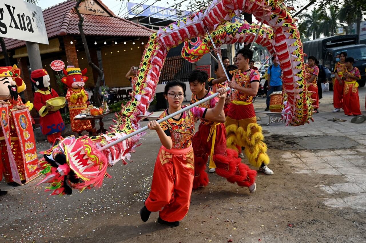 This photograph taken on January 21, 2021 shows Le Yen Quyen (C) of the Tu Anh Duong lion and dragon dance school performing a dragon dance outside a newly-opened cafe in Can Tho city in southern Vietnam's Mekong Delta.