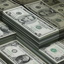 montones de billetes de dólar reflejados en vidrio