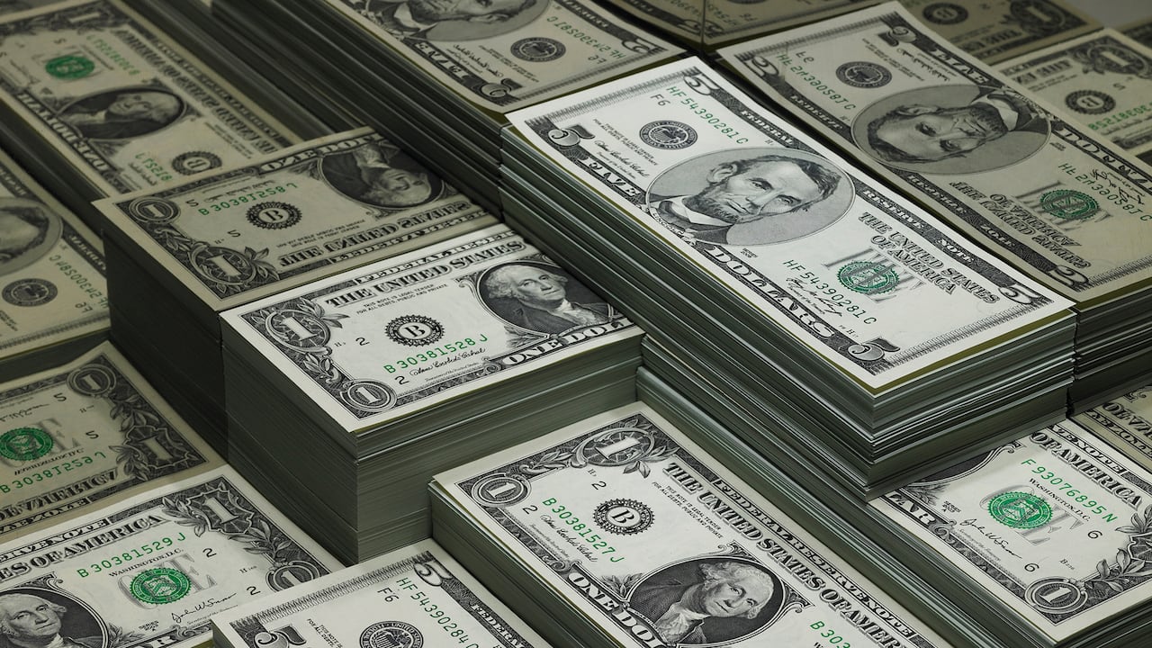 Montones de billetes de dólar reflejados en vidrio