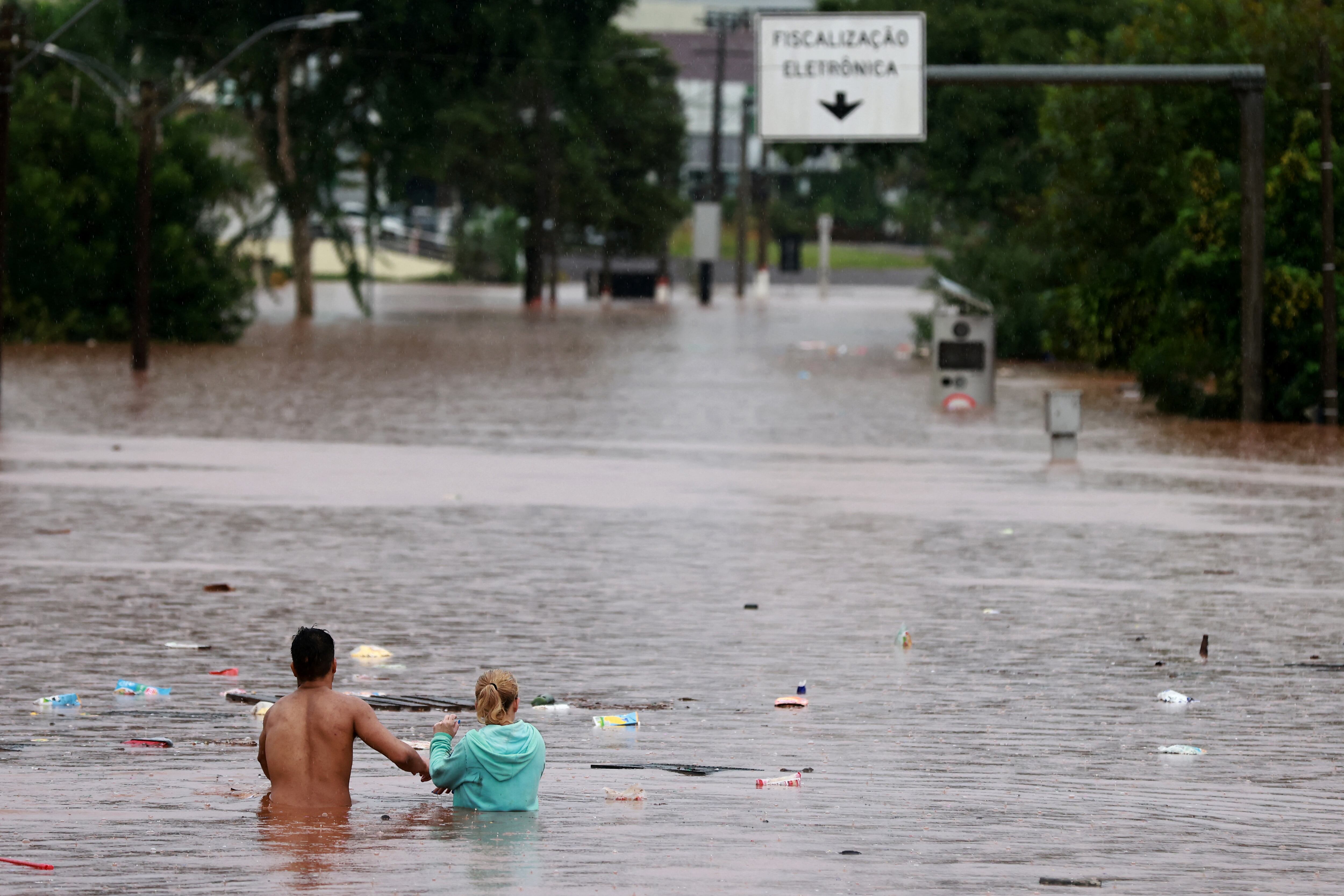 La gente camina en una zona inundada junto al río Taquari durante las fuertes lluvias en Encantado, estado de Rio Grande do Sul, Brasil, 2 de mayo de 2024.