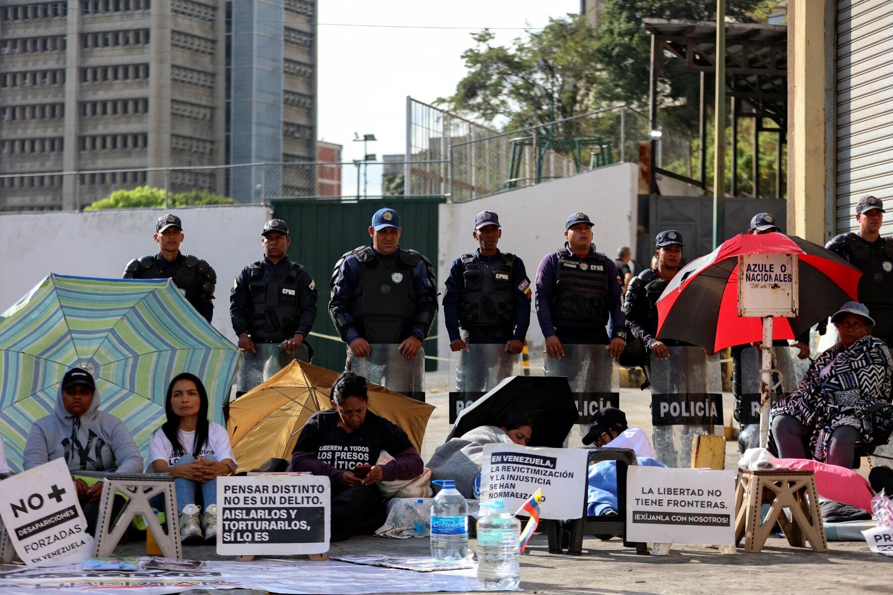 Familiares de presos políticos protestan frente a una fila de policías frente a la cárcel Zona 7 de la Policía Nacional Bolivariana (PNB)