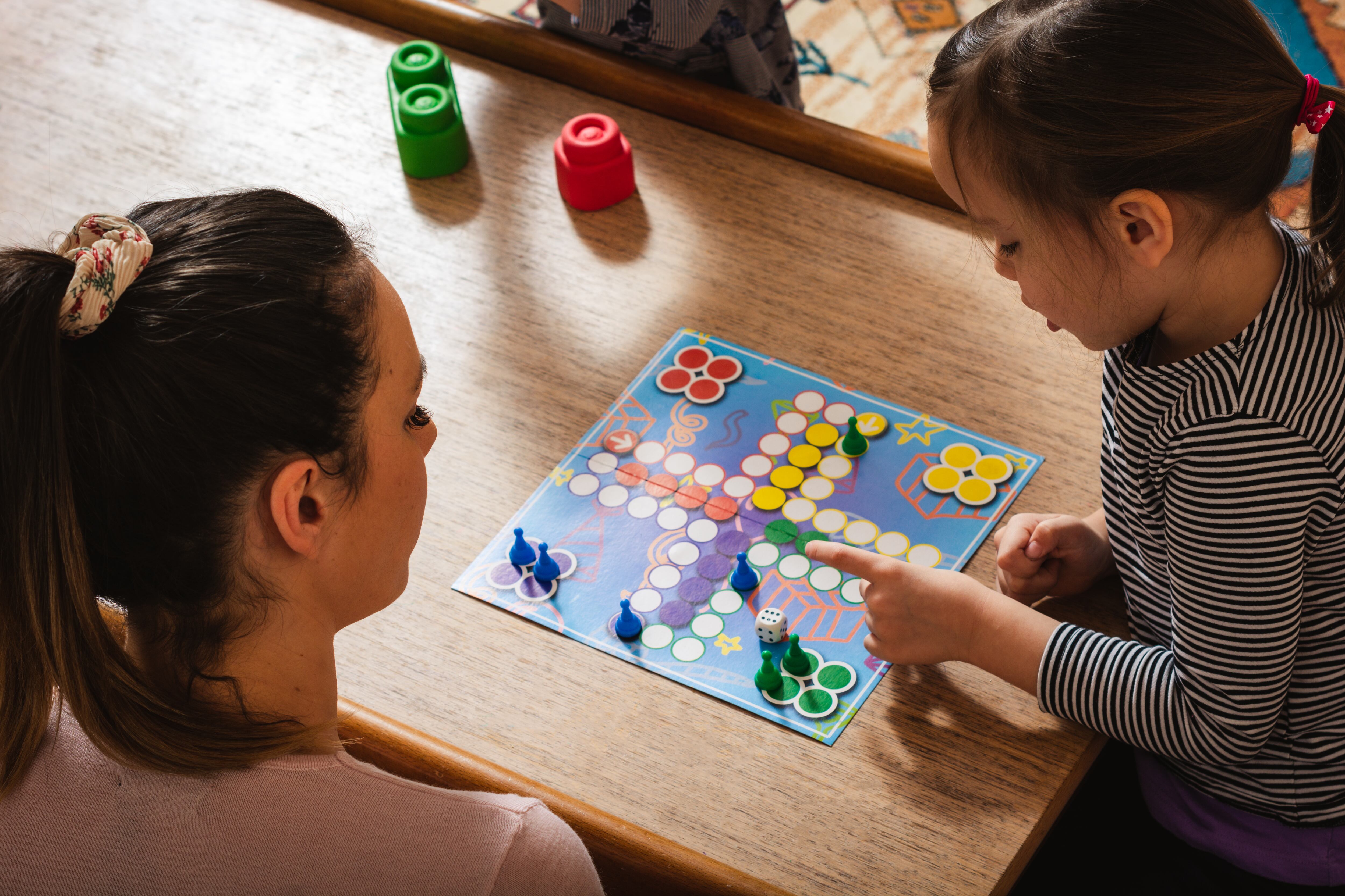 Madre e hija jugando juegos de mesa en casa.