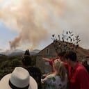 La gente en el pueblo de Grimaud, en el departamento de Var, observa cómo los incendios forestales se desatan en el sureste de Francia el 17 de agosto de 2021. (Photo by Valery HACHE / AFP)