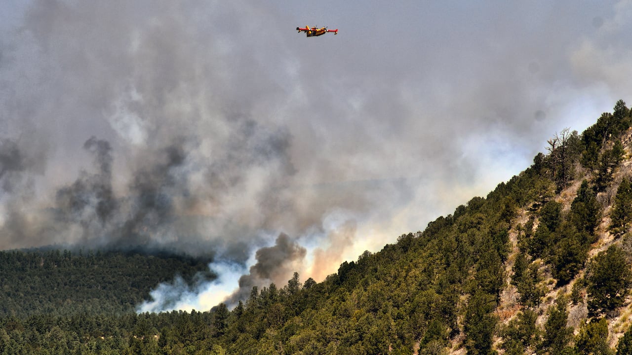 Un avión para combatir incendios vuela sobre un incendio forestal el miércoles 4 de mayo de 2022, cerca de la ciudad de Las Vegas, Nuevo México. (AP Foto/Thomas Peipert)
