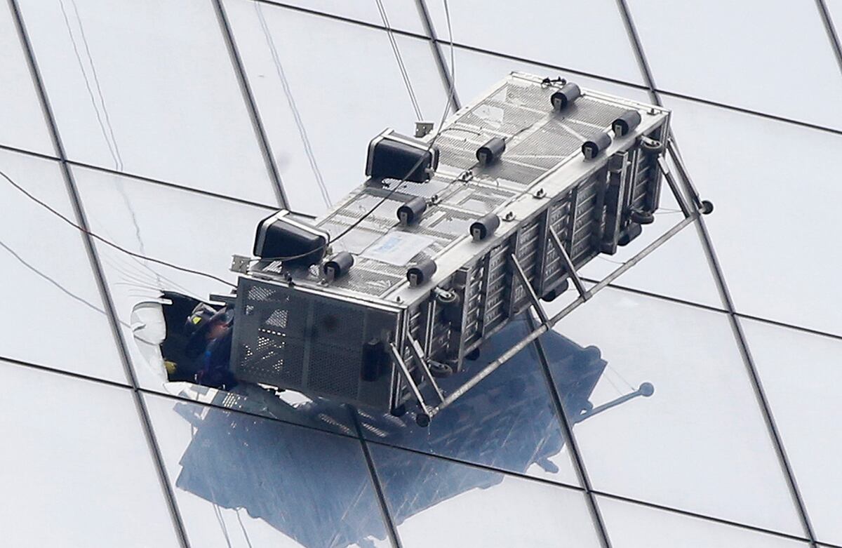 Un bombero intenta rescatar, a través de una ventana cortada provisionalmente, a dos limpiadores de vidrios que quedaron colgando durante más de una hora en el exterior del 1 World Trade Center en Nueva York, Estados Unidos. (AP)