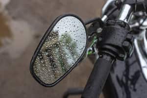 Reflection in the mirror. Raindrops on a motorcycle mirror. Traveling on two wheels. Motorcycle travel in any weather. Walk under the rain. Drops close up. The romance of biker life.