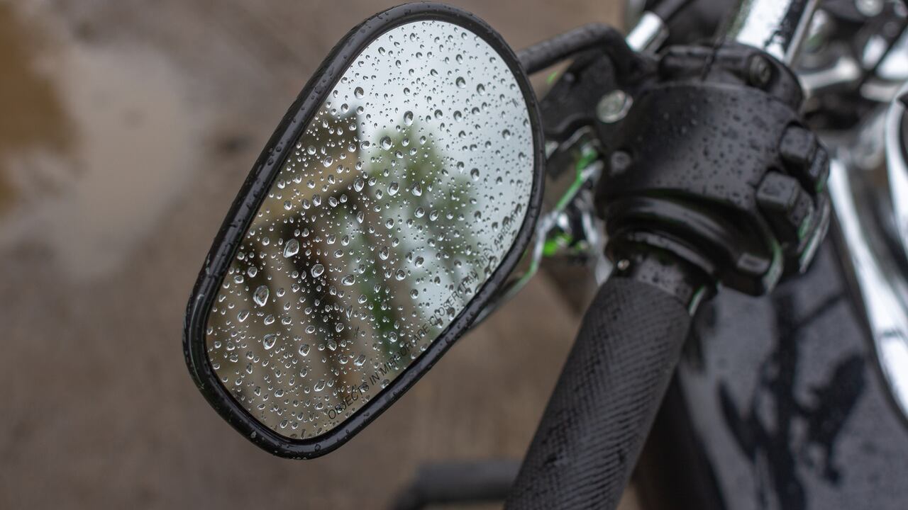 Reflection in the mirror. Raindrops on a motorcycle mirror. Traveling on two wheels. Motorcycle travel in any weather. Walk under the rain. Drops close up. The romance of biker life.