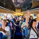 Grupo de turistas celebrando en un autobús, listos para comenzar su viaje.