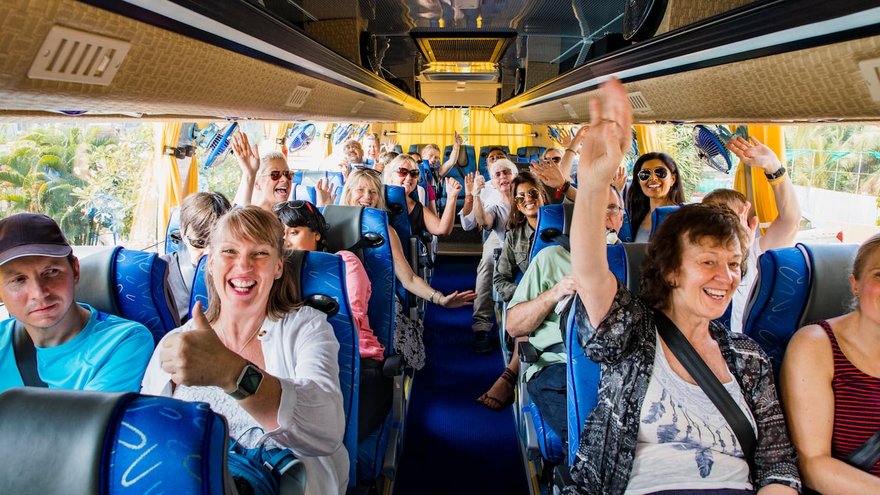 Grupo de turistas celebrando en un autobús, listos para comenzar su viaje.