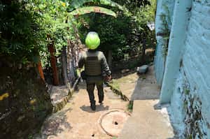 Un oficial de la Policía de Cali camina por el sector 'El tierrero', es Siloé mientras busca a las niñas que protagonizaron un video donde dos menores de edad le dan marihuana a una menor de 4 años. Foto: Wirman Ríos