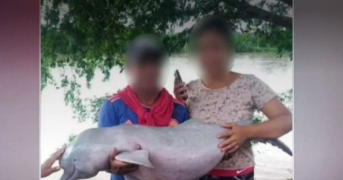 Foto de mujer y hombre posando con delfín rosado en Caquetá.