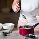 Woman making morning breakfast oatmeal cereals and adding ingredients in the kitchen at home. Making healthy organic meal packed with fiber and nutrients