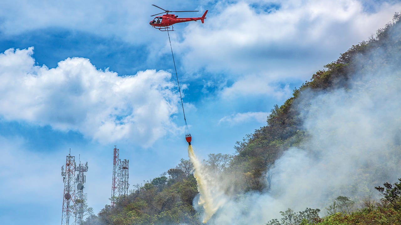 Riego sobre una montaña para controlar los incendios en las zonas afectadas