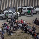 Los migrantes se sientan en filas frente a las fuerzas de seguridad estadounidenses en el área entre los dos muros que separan a México de los Estados Unidos.