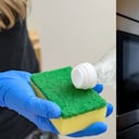 Persona limpia un electrodoméstico con vinagre blanco.