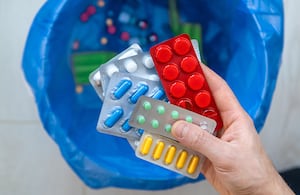 Persona se dispone a botar varios sellos de medicamentos en la basura.