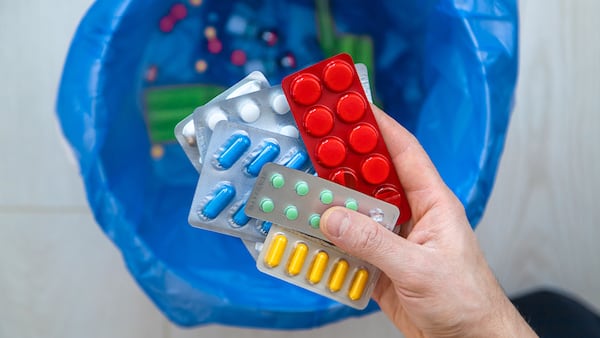 Persona se dispone a botar varios sellos de medicamentos en la basura.