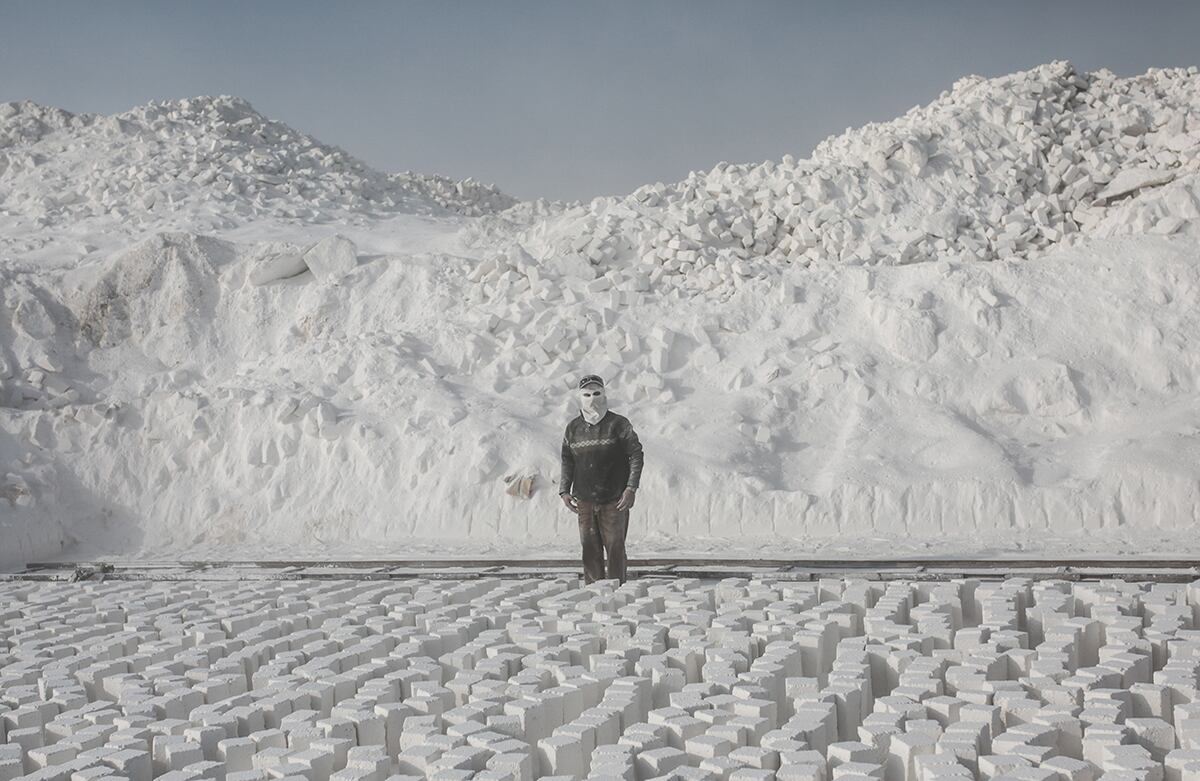 Un hombre, que viste una máscara para proteger sus rostro del polvo, se prepara para recoger piedras recién cortadas de la cantera del desierto de Menia, Egipto. (AP)