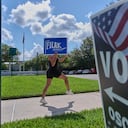 Yvette Allen, de Celebration, Florida, hace ejercicio mientras sostiene un cartel de la elección de la junta escolar local frente a la biblioteca West Osceola Branch, durante la votación anticipada para las elecciones primarias de Florida en Celebration, Florida, el jueves 13 de agosto de 2026.