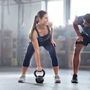 Strong, wellness couple doing kettlebell weight exercise, workout or training inside a gym. Happy sports people or trainer motivation, exercising with fitness equipment for muscle, strength or health