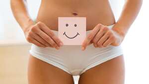 Primer plano de mujer joven sosteniendo papel con marca de sonrisa sobre su estómago. Concepto de educación sexual de higiene de la salud.