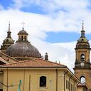 The view of the dome and bell towers of Primatial Cathedral of Bogota (Metropolitan Cathedral Basilica of the Immaculate Conception) in La Candelaria the historical center of Bogota with Colombian flag in foreground. Bogota.Colombia. 05/2017