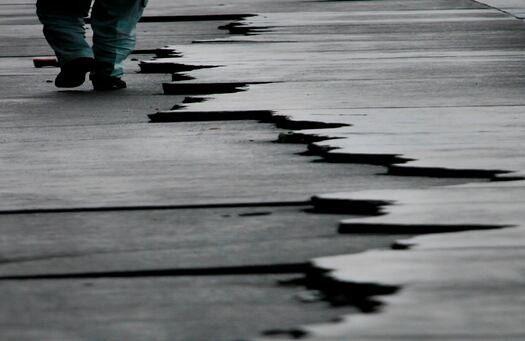 Un hombre camina por las grietas que dejaron el terremoto, de 6.6 grados de magnitud, en el puerto de Yaizu. 