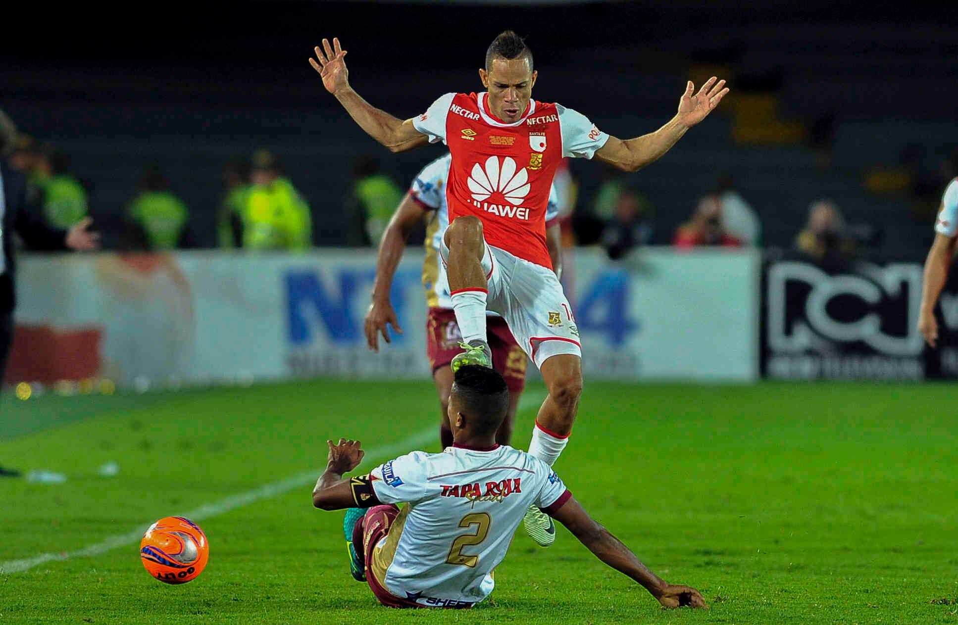 Anderson Plata, del Santa Fe, salta sobre Fainer Torijano, del Tolima, durante el partido de vuelta de la final del torneo de fútbol profesional colombiano, el domingo 18 de diciembre de 2016, en el Campín, en Bogotá.Al finalizar el partido los cardenales alcanzaron su novena estrella al derrotar 1-0 a los tolimenses, con un gol de Héctor Urrego.