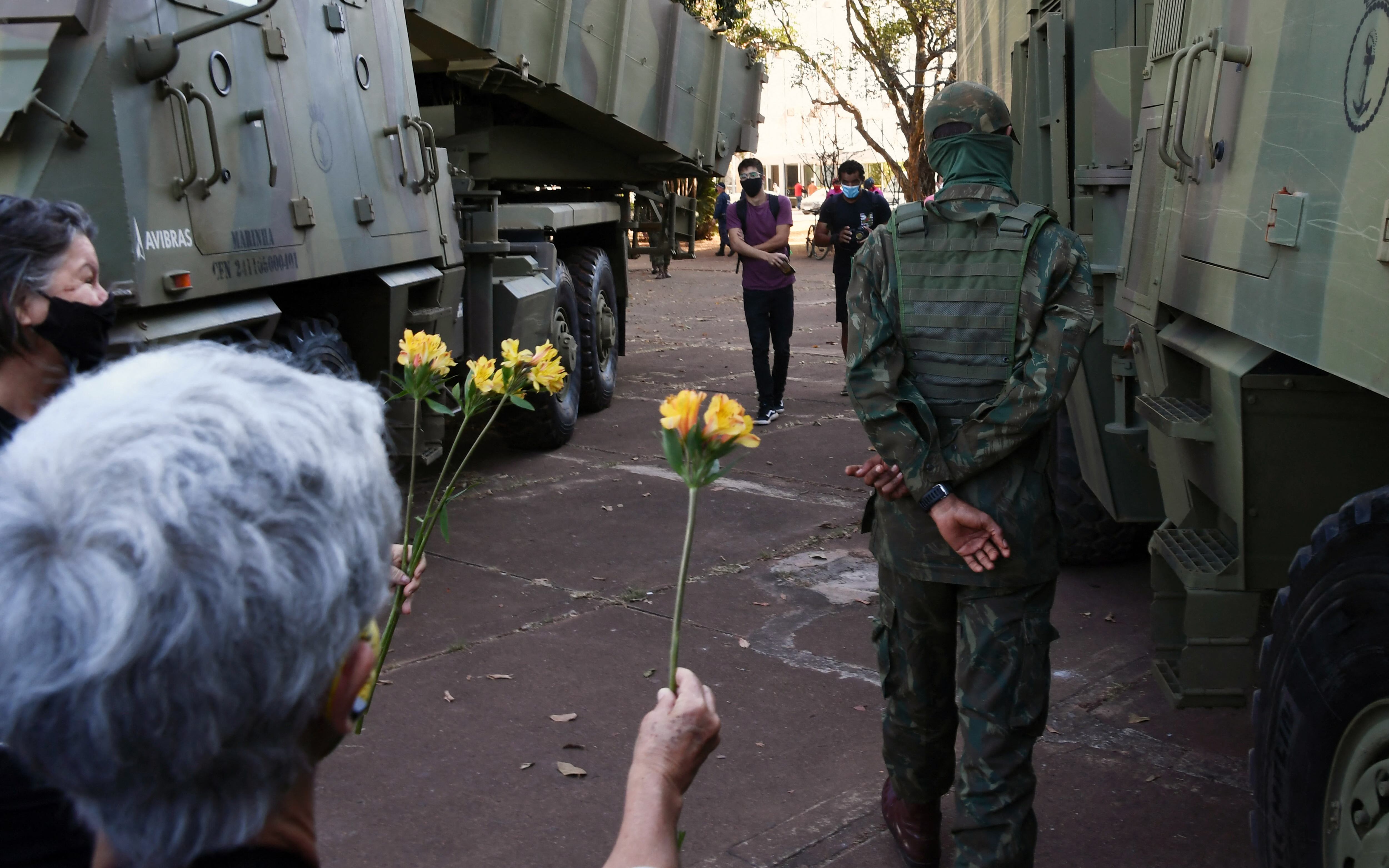 Manifestantes contra un desfile de vehículos militares frente al Palacio Planalto en Brasilia, ofrecen flores a un soldado, el 10 de agosto de 2021. - Bolsonaro es acusado de utilizar a las Fuerzas Armadas en una demostración de fuerza para intimidar al Congreso Nacional, donde se encuentra un proyecto de ley. Se está debatiendo la modificación del sistema de votación electrónica. (Foto de EVARISTO SA / AFP)