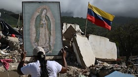 Una mujer sostiene una imagen de la Virgen de Guadalupe mientras voluntarios y familiares de las víctimas buscan los cuerpos de sus seres queridos entre los escombros de un edificio destruido por los terremotos del 24 de junio en Caraballeda, Venezuela, el 17 de julio de 2026.