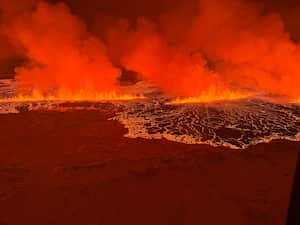Billowing smoke and flowing lava turning the sky orange are seen in this Icelandic Coast Guard handout image during an volcanic eruption on the Reykjanes peninsula 3 km north of Grindavik, western Iceland on December 18, 2023. A volcanic eruption began on Monday night in Iceland, south of the capital Reykjavik, following an earthquake swarm, Iceland's Meteorological Office reported. (Photo by Icelandic Coast Guard / HANDOUT / AFP) / RESTRICTED TO EDITORIAL USE - MANDATORY CREDIT "AFP PHOTO / " - NO MARKETING NO ADVERTISING CAMPAIGNS - DISTRIBUTED AS A SERVICE TO CLIENTS
