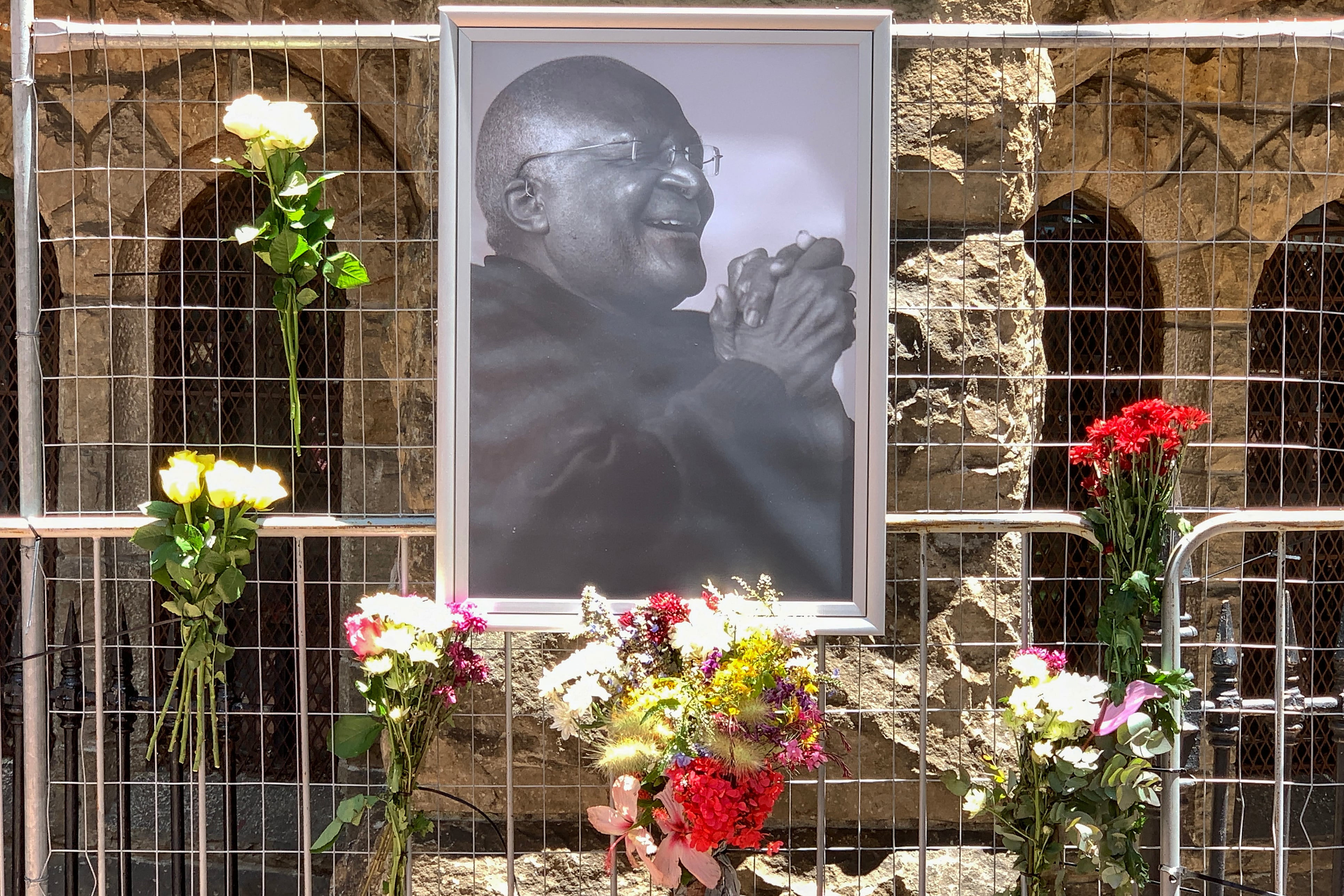 Flores junto a un retrato del ícono sudafricano anti-apartheid Desmond Tutu afuera de la catedral de San Jorge en Ciudad del Cabo el 26 de diciembre de 2021, luego de la noticia del fallecimiento de Tutu. - El ícono sudafricano anti-apartheid Desmond Tutu, descrito como la brújula moral del país, murió el 26 de diciembre de 2021, a los 90 años.(Photo by Gianluigi GUERCIA / AFP)