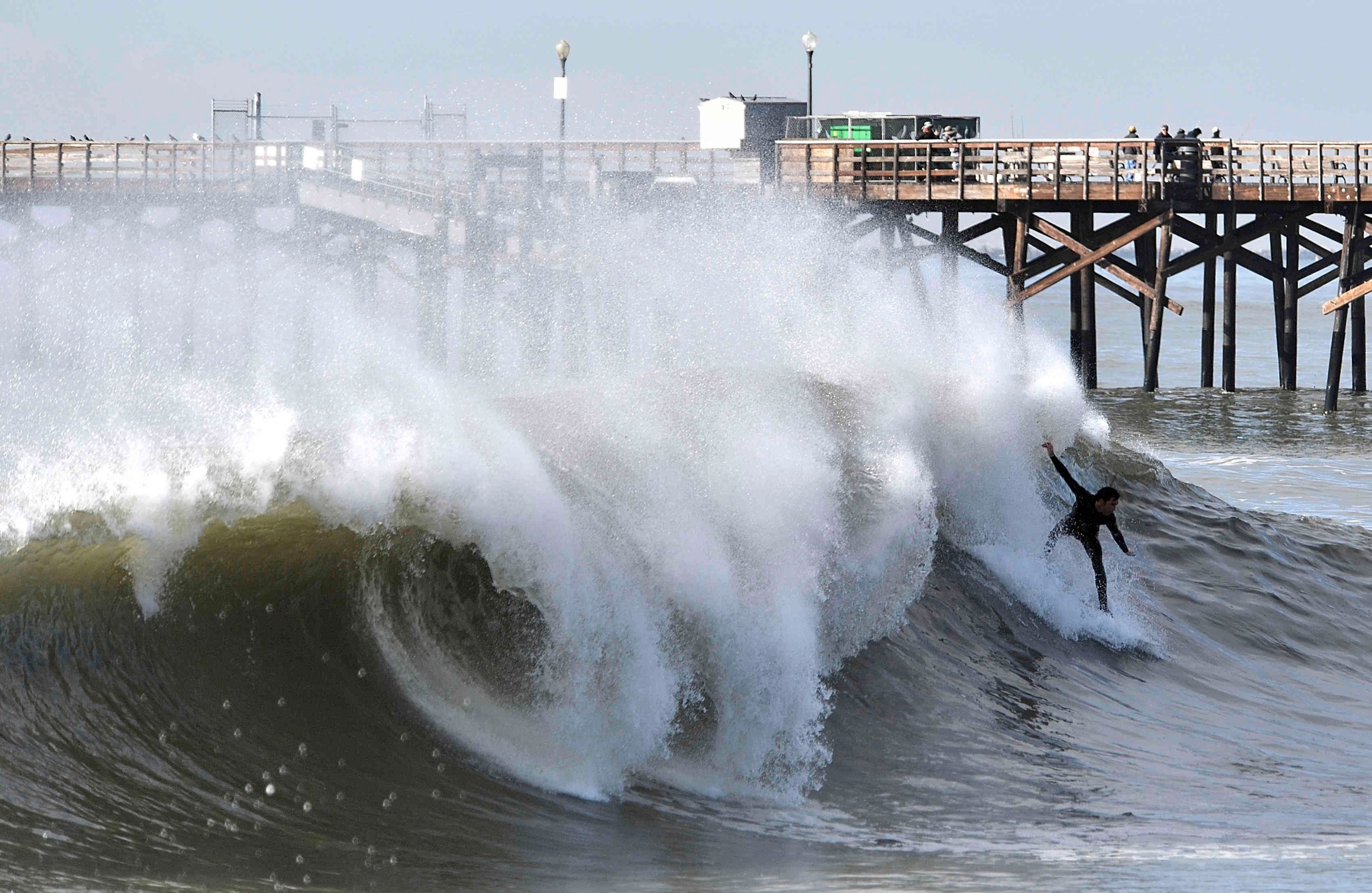 Surfistas montan las olas en el lado sur de Seal Beach Pier después de una serie de poderosas tormentas de invierno en Seal Beach, California, el martes 24 de enero de 2017. (Jeff Gritchen / The Orange County Register vía AP)