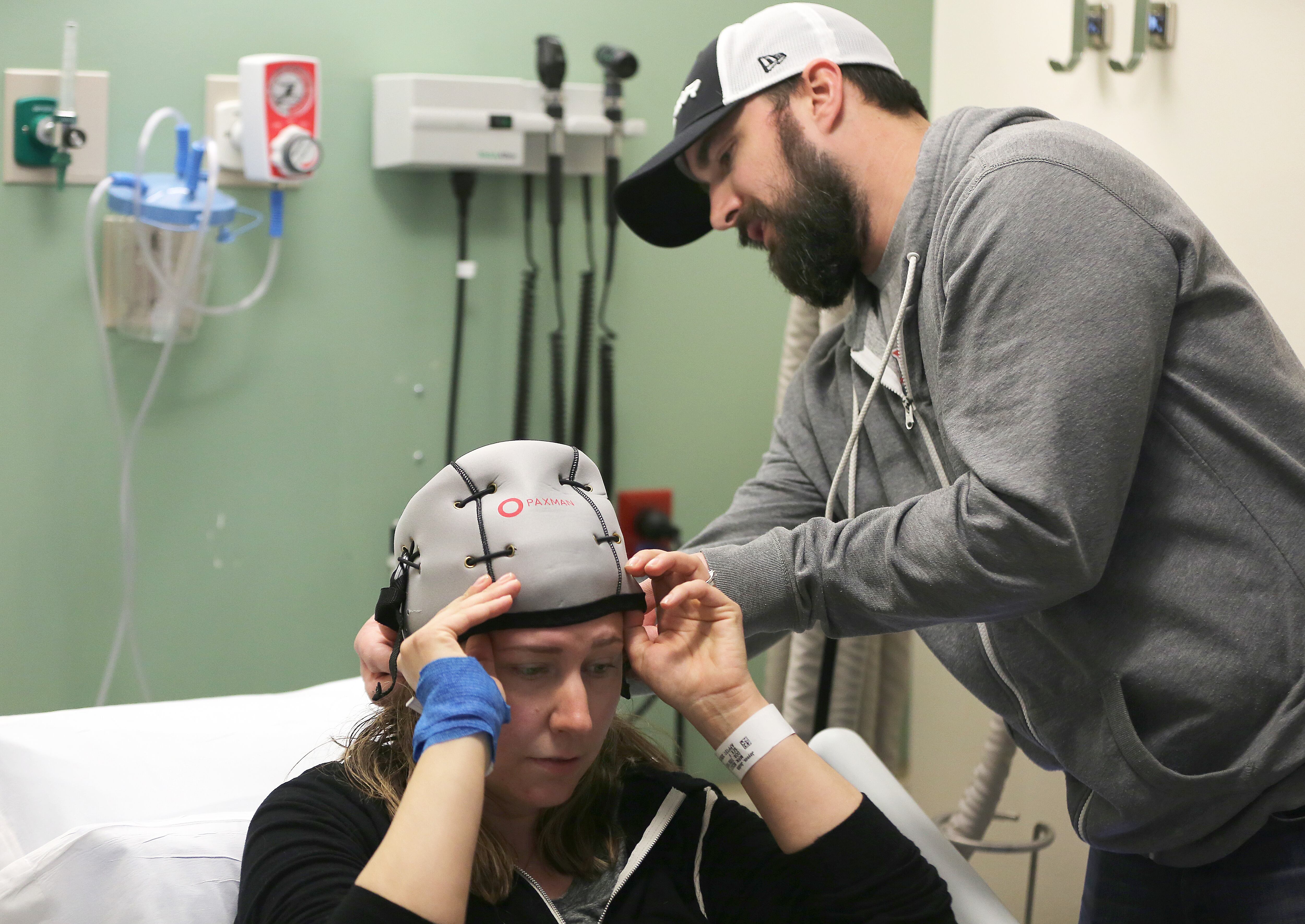 Steve Jaynes ayuda a su esposa Judith Jaynes, una paciente con cáncer de mama, a colocarse un gorro frío antes de una sesión de quimioterapia en el Instituto del Cáncer Dana-Farber en Boston el 29 de marzo de 2018.
