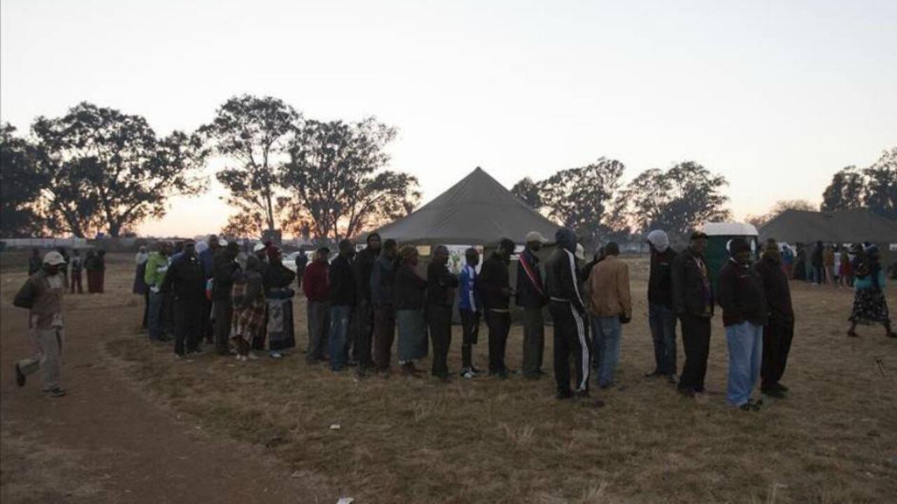 Las personas esperan en fila para poder ejercer su derecho al voto en las elecciones generales de Zimbabue en su capital, Harare.
