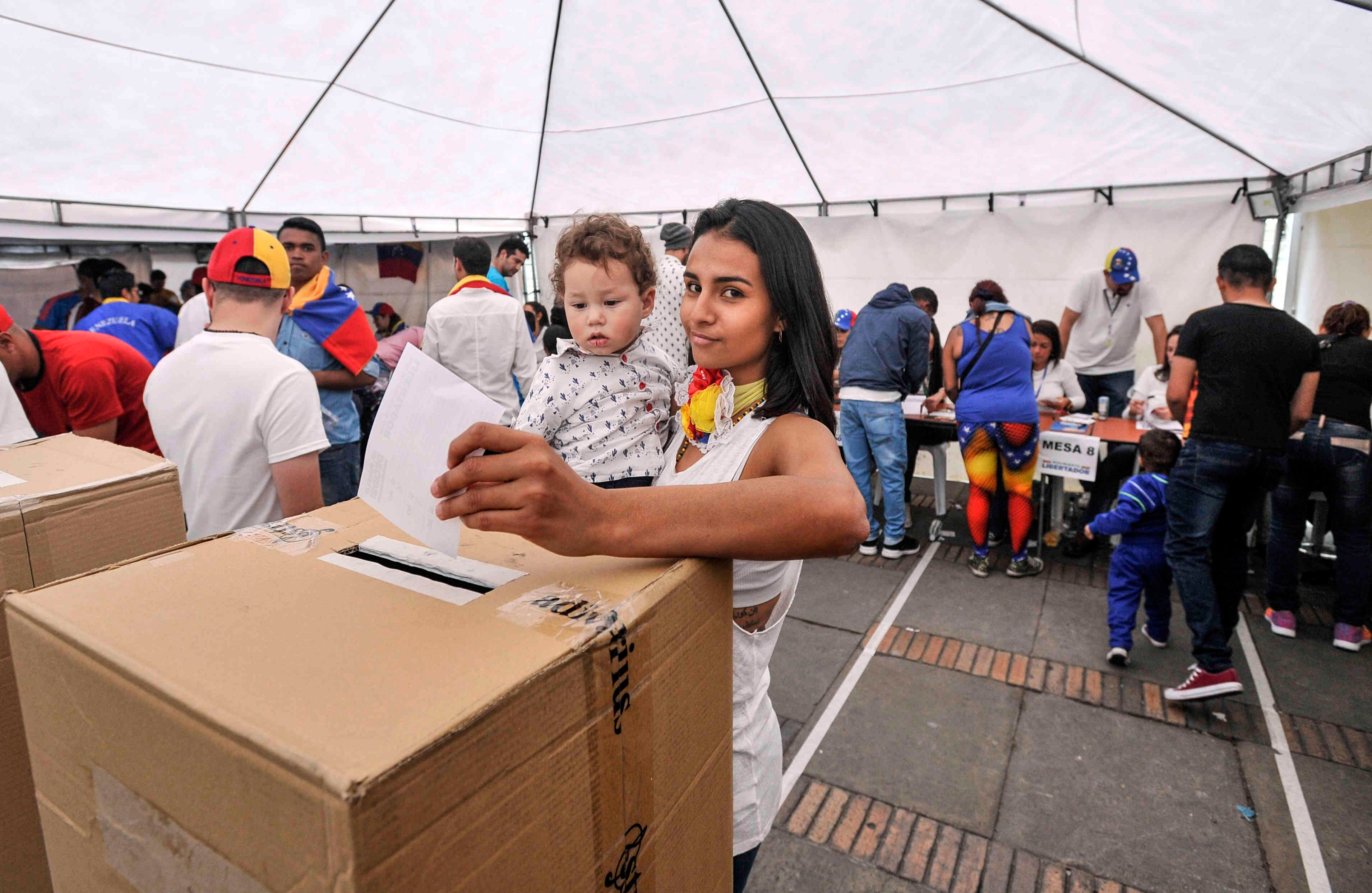 . Una venezolana  —residente en Bogotá— carga a su pequeño hijo mientras  sufraga, el domingo 16 de julio de 2017, en Colombia, durante las votaciones al plebiscito. Esta jornada democrática ha sido  impulsada  por la oposición al gobierno de Nicolás Maduro. En las tarjetas, los ciudadanos deben responder ‘sí’ o ‘no’ a tres preguntas: la primera es si respalda el plan del presidente Nicolás Maduro de cambiar la Constitución; la segunda es si  apoya la intervención de las Fuerzas Armadas para “restituir el orden constitucional” y por último si desea un gobierno de unidad nacional. Foto: Carlos Julio Martínez / SEMANA