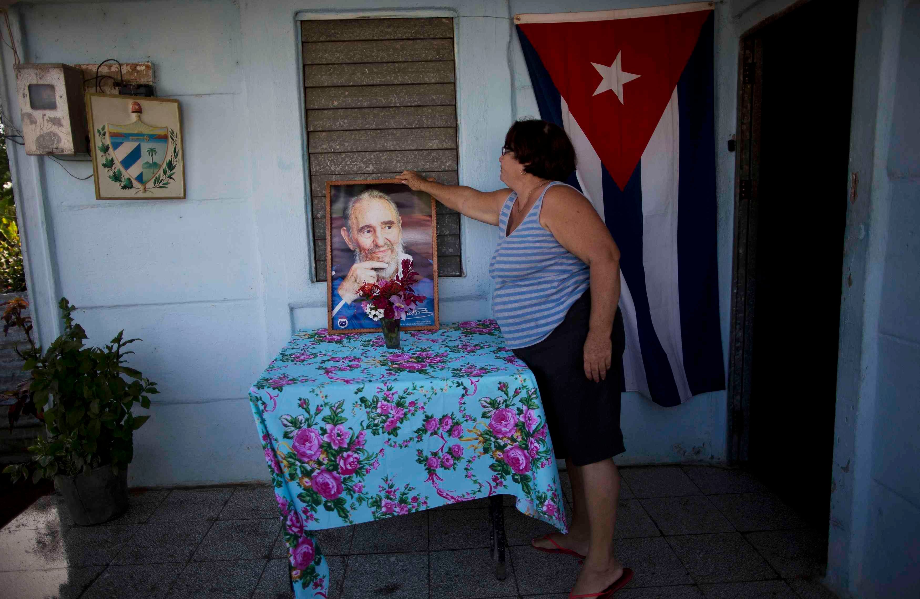 Verónica Santo  acomoda la foto de Fidel Castro en su carro en Camaguey, Cuba (AP Photo/Rodrigo Abd)