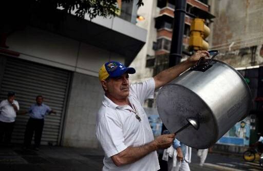 Un opositor alienta a los manifestantes con el sonido de una olla. Crédito:  FEDERICO PARRA / AFP