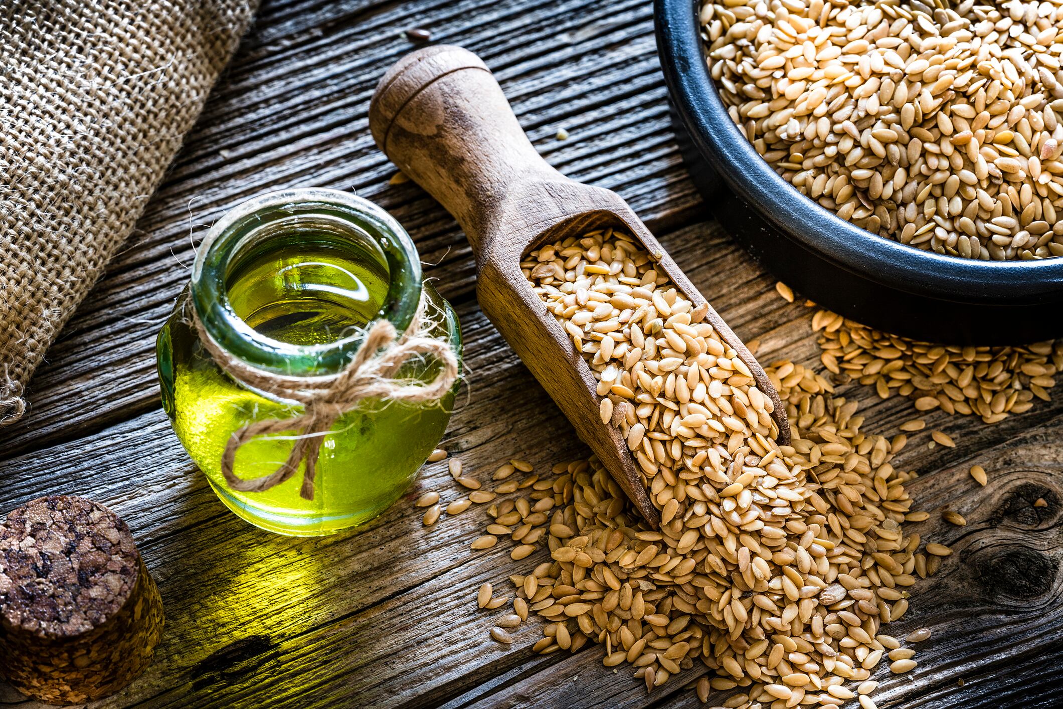 Flax seed oil and brown flax seeds shot on rustic wooden table. Flax seed oil is rich in Omega 3. Predominant colors are brown and yellow. XXXL 42Mp studio photo taken with Sony A7rii and Sony FE 90mm f2.8 macro G OSS lens