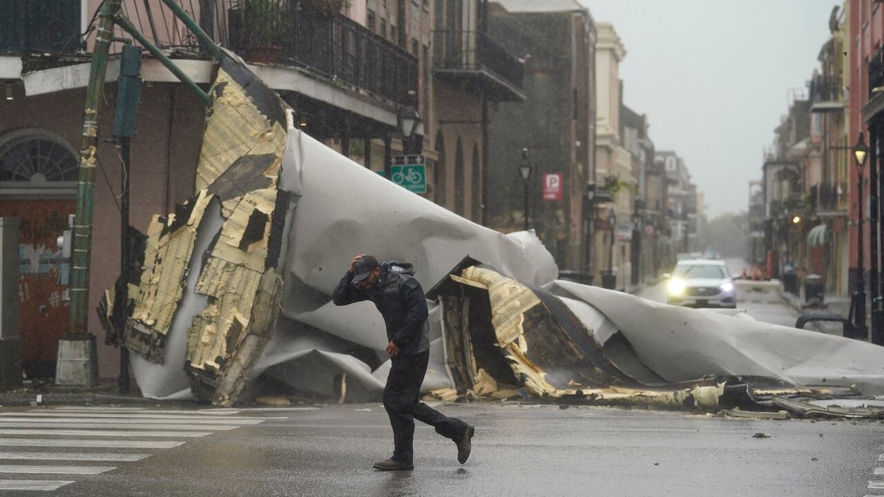 Un hombre camina frente a la parte de un techo que fue arrancado de un edificio por los vientos del huracán Ida, el domingo 29 de agosto de 2021, en Nueva Orleans. (AP Foto/Eric Gay)