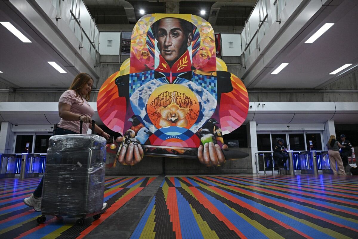 A passenger walks along an alley at Simon Bolivar International Airport in Maiquetia, La Guaira State, Venezuela, on November 27, 2025. Venezuela's decision to ban foreign airlines that stopped flying to the Caribbean country over concerns about US military activity was branded "disproportionate" on Thursday as thousands of passengers scrambled to save their travel plans. (Photo by Federico PARRA / AFP)