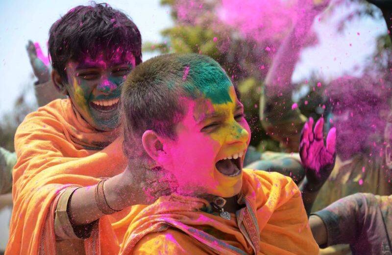 Un estudiante mancha polvo coloreado en la cara de otro mientras celebran el festival Holi en la escuela. El polvo de colores se llama "gulal" y originalmente se hacía con cúrcuma, pasta y extractos de flores. FOTO: Uma Shankar MISHRA / AFP.