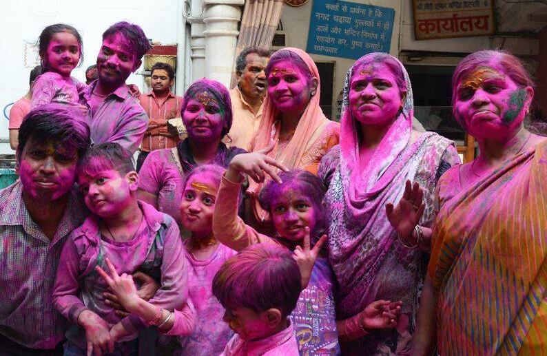 Una familia india cubierta de polvo de colores posa para una foto mientras celebran Holi. FOTO: Dominique FAGET / AFP.