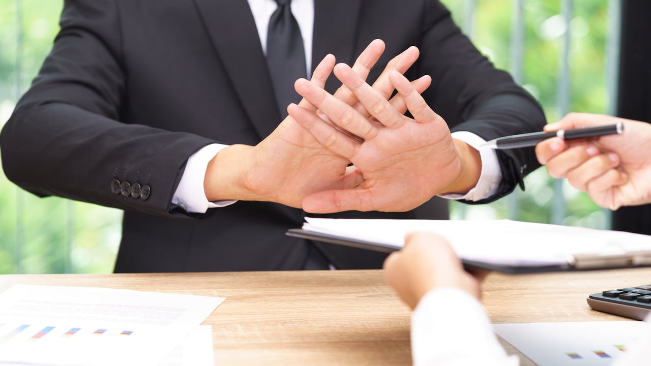 Cropped Hands Of Person Giving Documents And Pen To Sign While Man Refusing Over Table