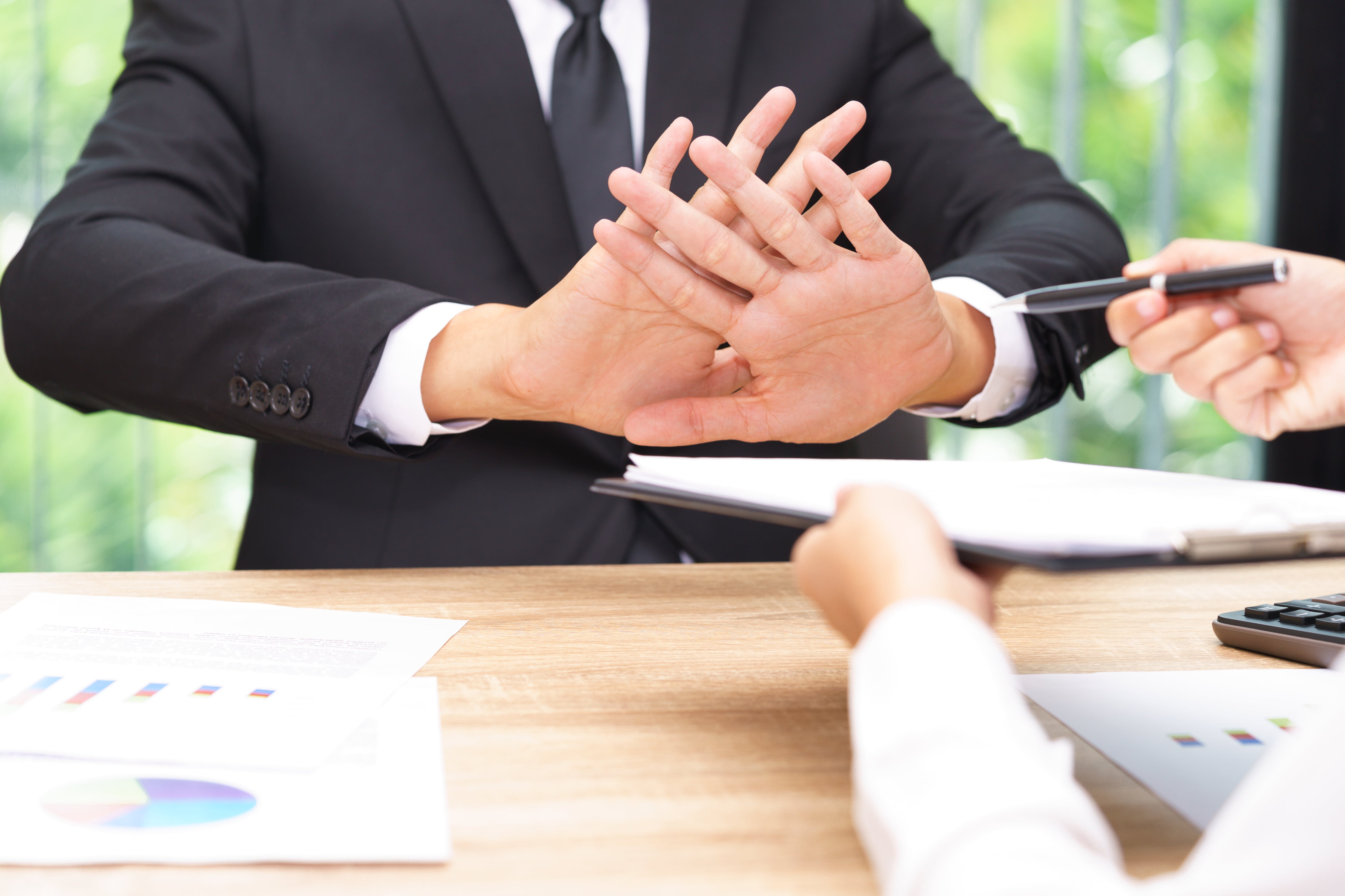 Cropped Hands Of Person Giving Documents And Pen To Sign While Man Refusing Over Table