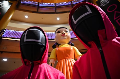 Cosplayers vestidos con atuendos de la serie de Netflix "El Juego del Calamar" junto a una estatua de muñeca en un centro comercial en Kuala Lumpur el 20 de octubre de 2021. (Photo by MOHD RASFAN / AFP)