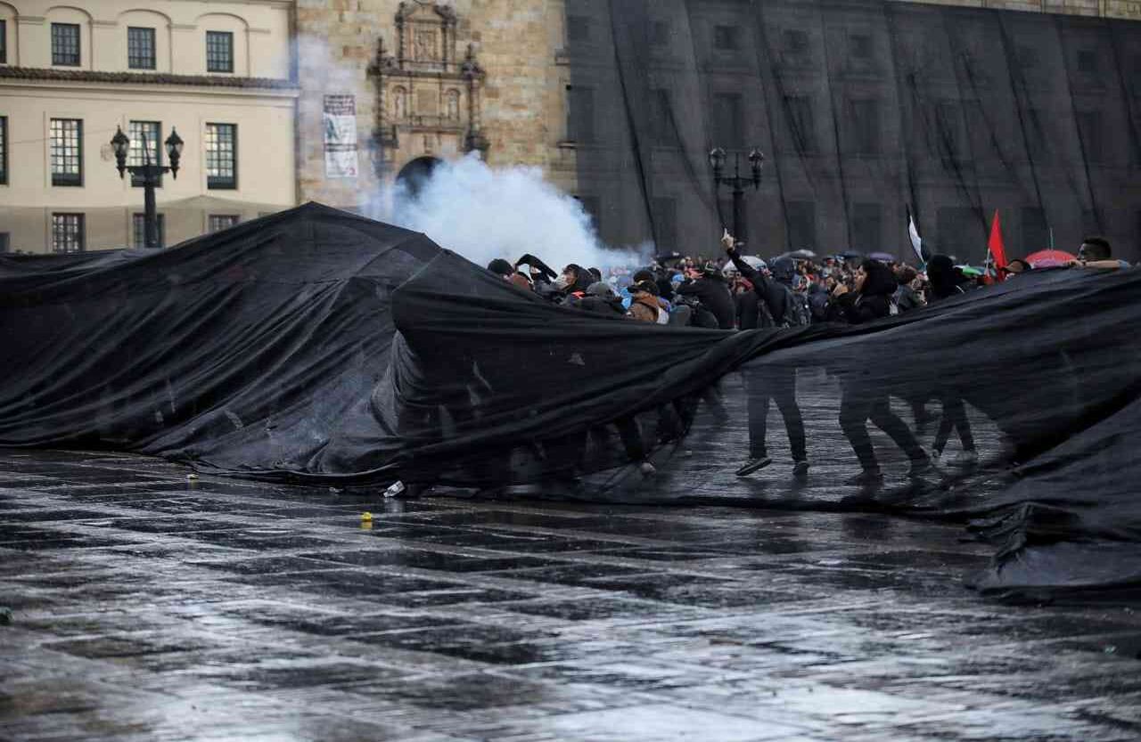 Los manifestantes se ocultan detrás de una malla.