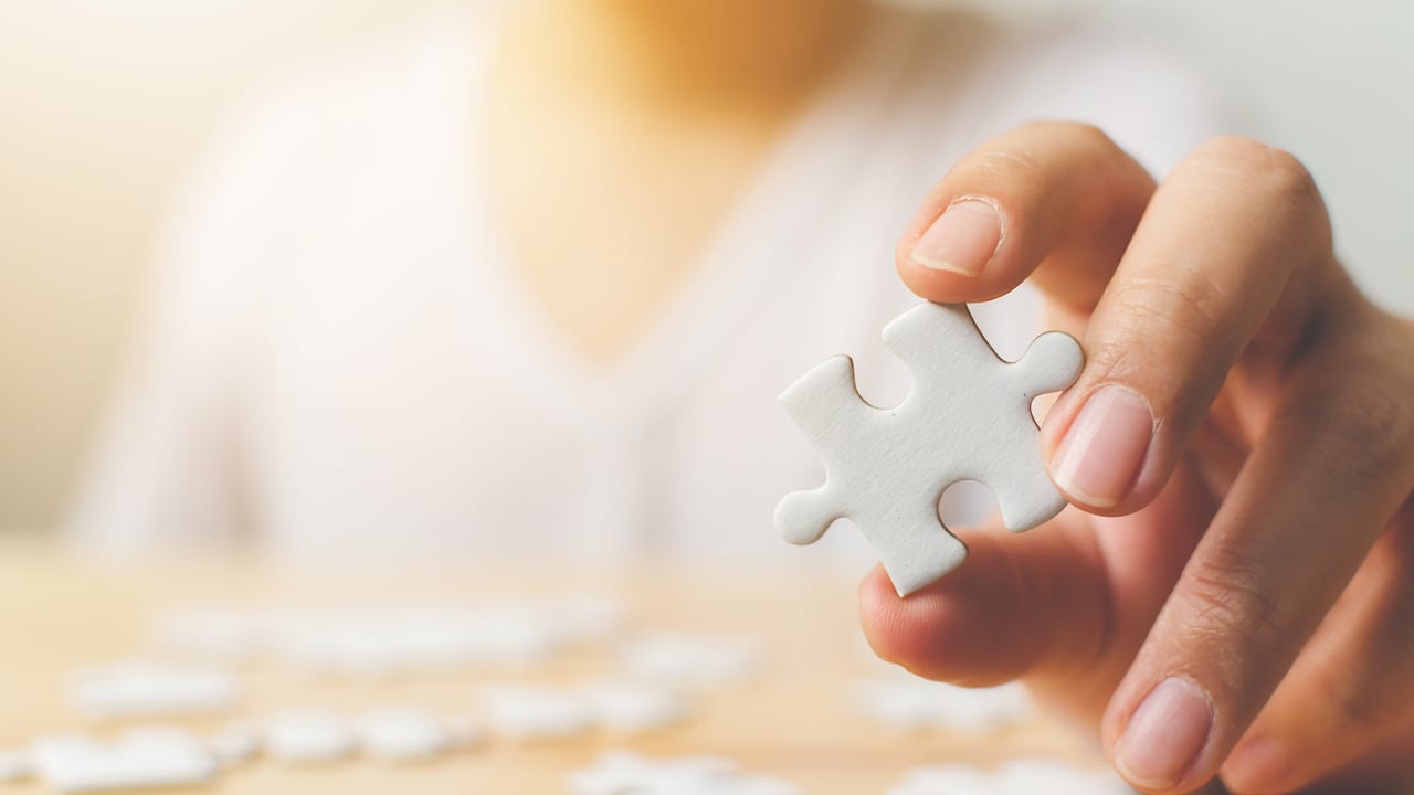 Mano de hombre tratando de conectar piezas de rompecabezas blanco sobre mesa de madera. Atención médica para la enfermedad de Alzheimer, la demencia, la pérdida de memoria, la conciencia del autismo y el concepto de salud mental