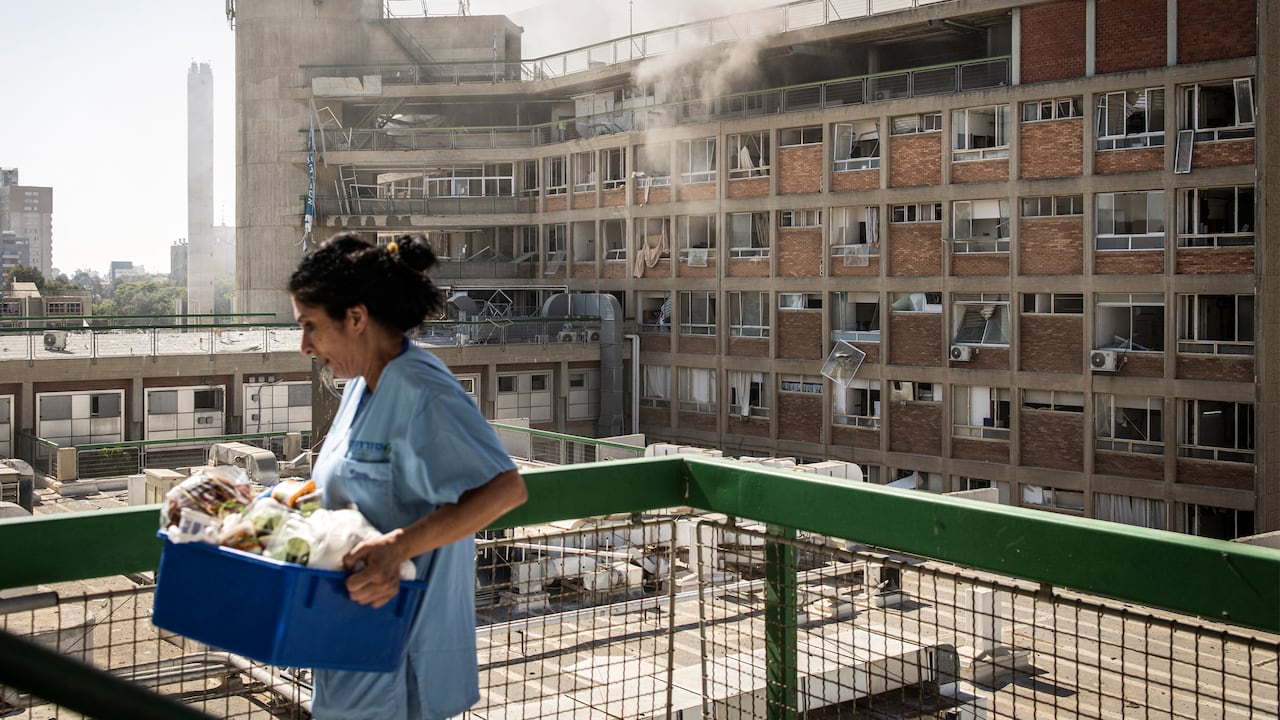 Una enfermera lleva suministros médicos frente a un edificio con columnas de humo en el Hospital Soroka tras un ataque con misiles iraníes en Beersheba, en el sur de Israel.
