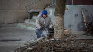 Un residente local prepara una comida en una estufa de madera cerca de su edificio, mientras continúan los ataques en Bajmut.